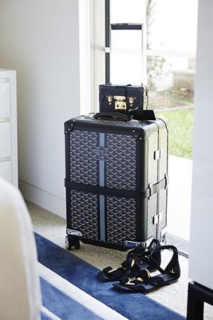 A MONOGRAMMED MAISON GOYARD SUITCASE SITS PRETTY IN ROXY’S BEDROOM