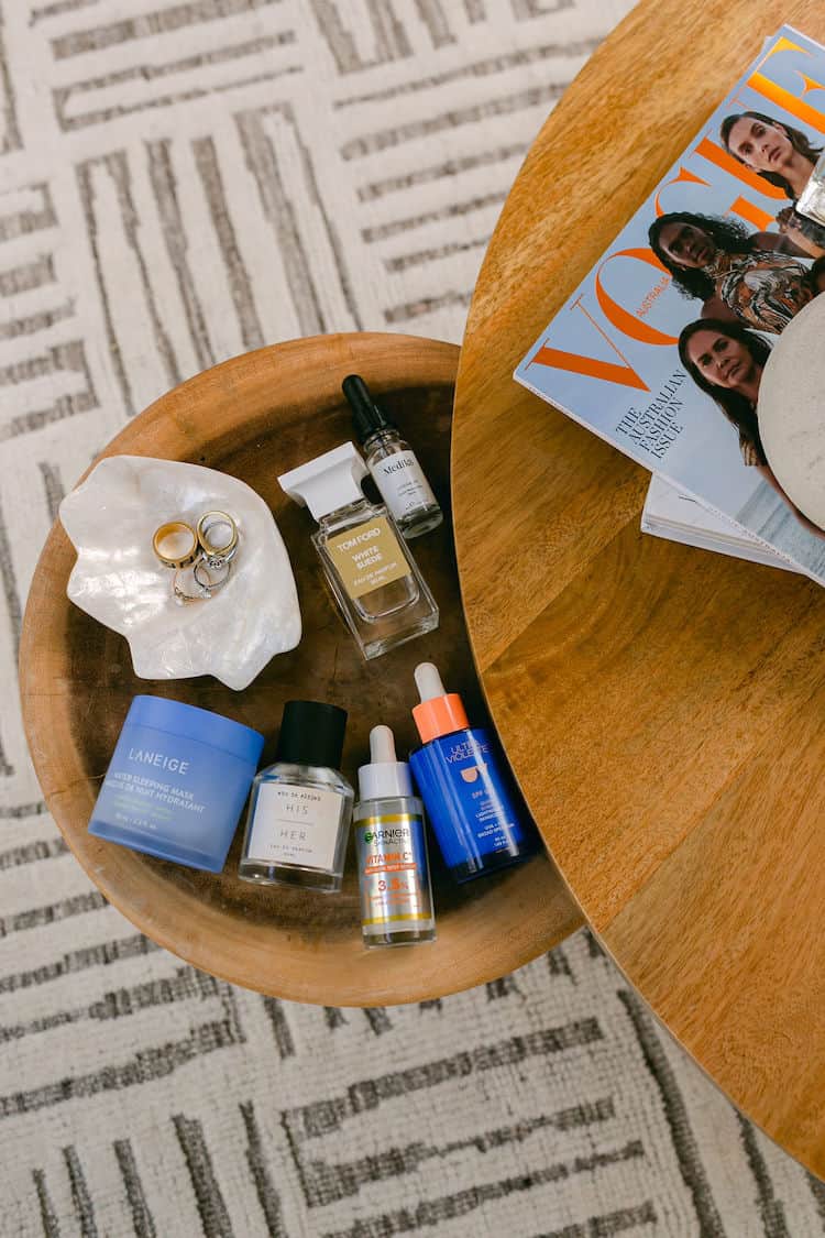 Flat lay of beauty products on a wooden tray including Laneige, Ultra Violette, Tom Ford and Burberry HER with Vogue magazine