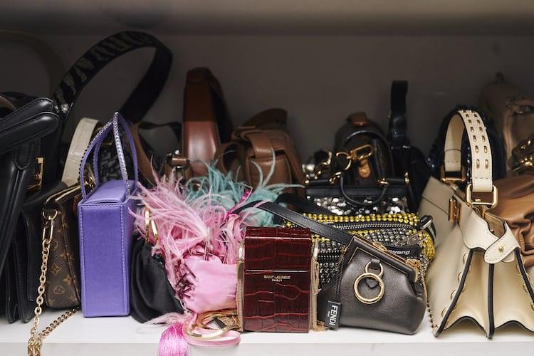 Shelf of designer handbags including Louis Vuitton, Saint Laurent, Fendi and feathered clutch