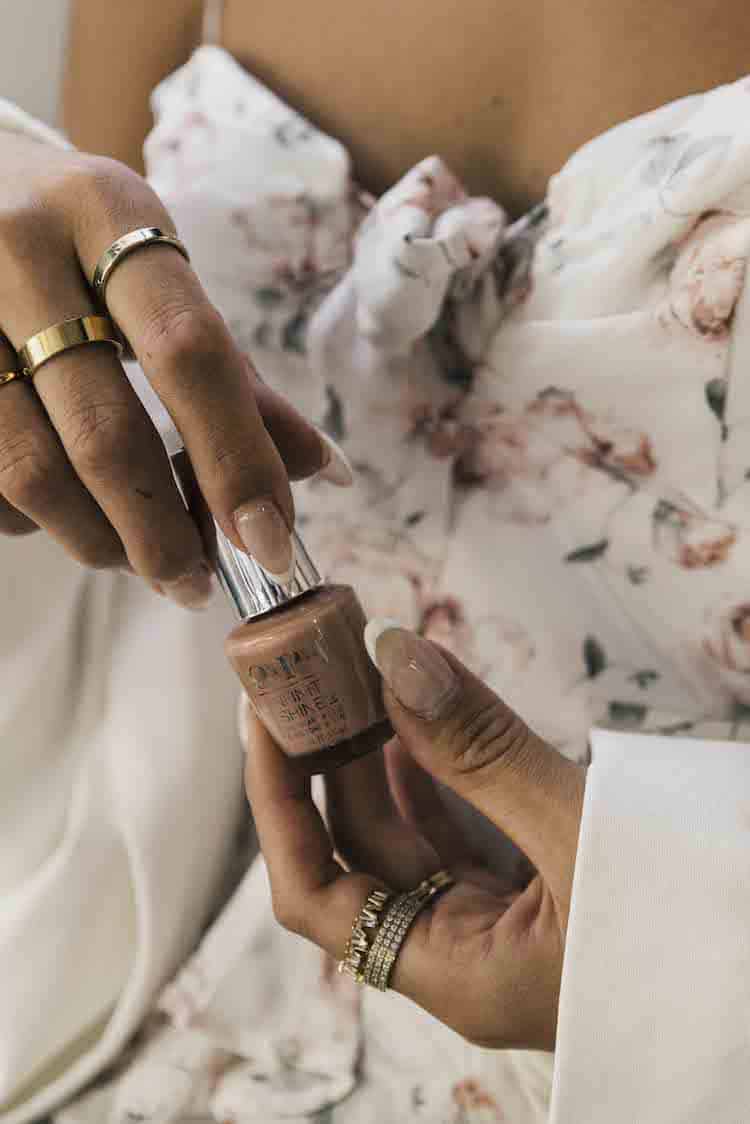 Riley Minford holding OPI nail polish with gold rings