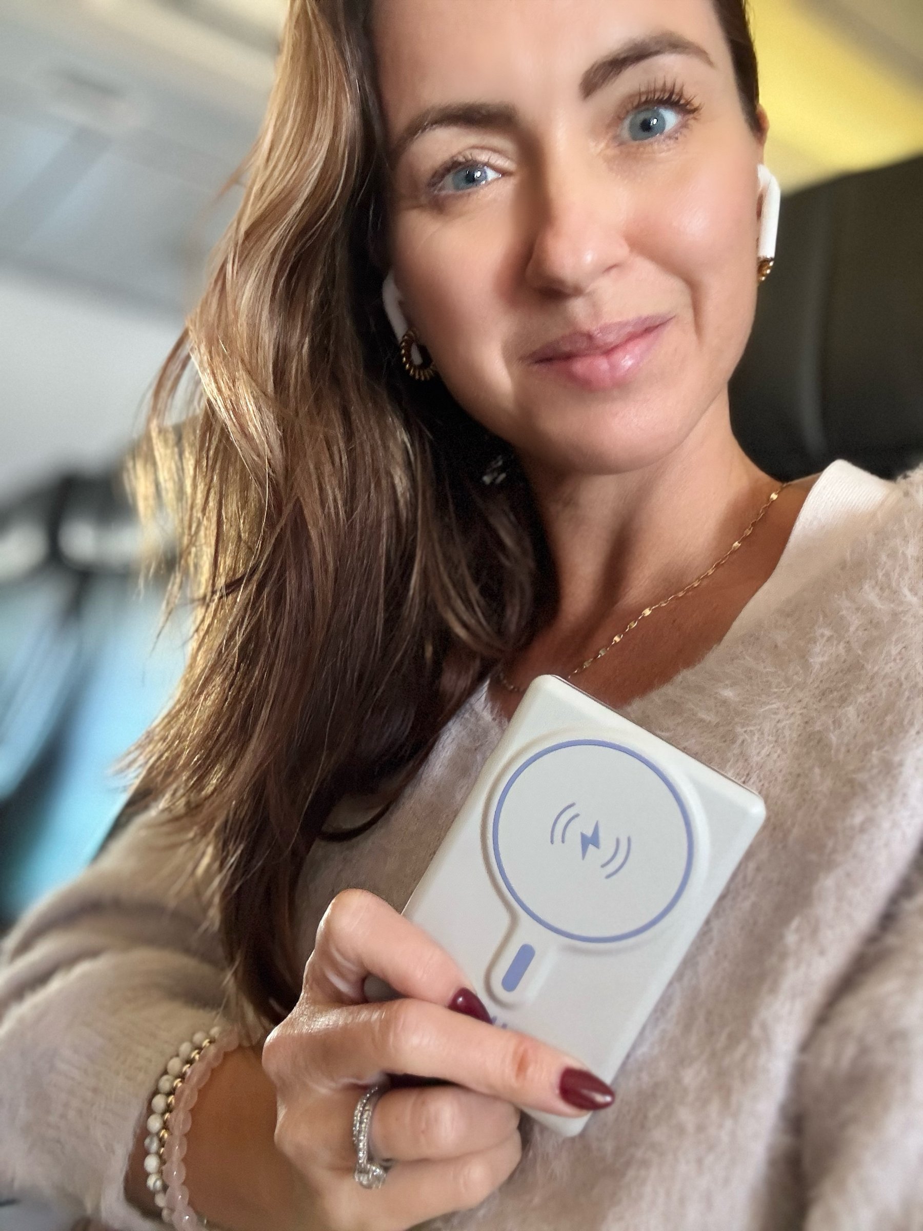 Sigourney Cantelo holding the Pulse Infinity Luxe wireless charger on a flight