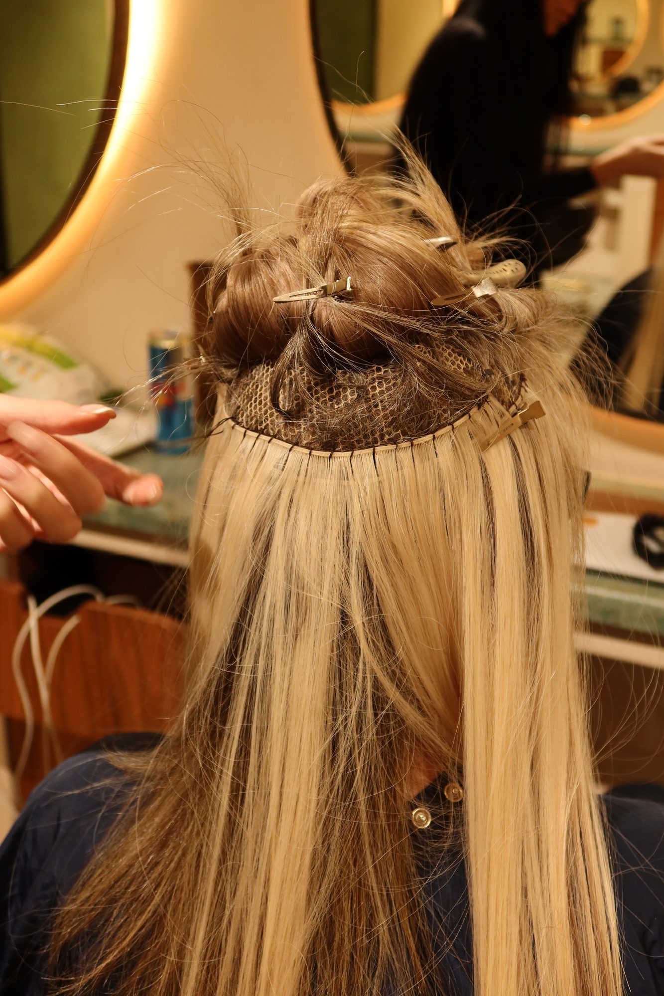 The back of Colette's head showing blonde extension wefts sewn in beneath her own hair
