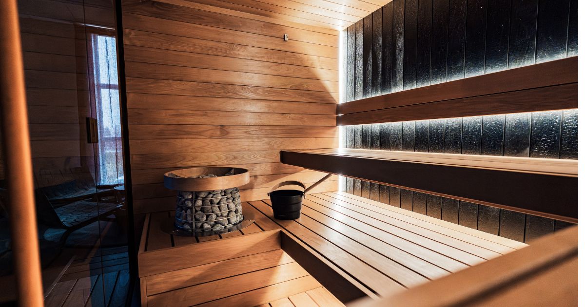 Interior of a luxury cedar sauna with ambient blue lighting and a traditional stone heater