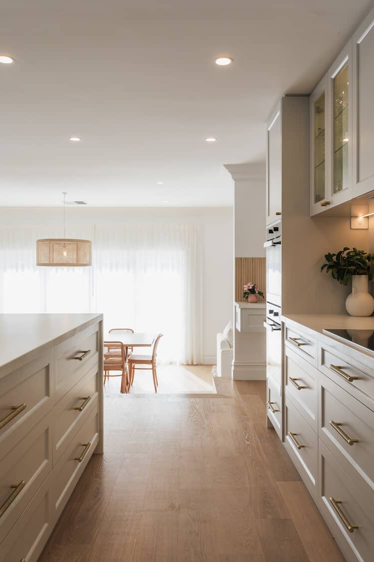 Clara's white Shaker-style kitchen with brass hardware, rattan pendant and oak flooring