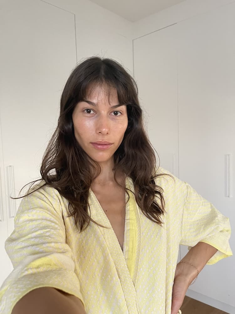 Helena Vestergaard at home in a yellow textured robe, wavy brunette hair with a fringe, bare-faced