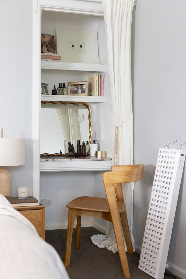 Minimalist self-care corner featuring an Infraredi red light therapy panel, wooden chair, and cozy decor in a sunlit wellness-inspired home space.