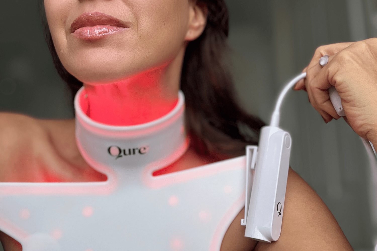 Qure Neck & Décolletage LED Mask switched on with red light therapy glowing across the skin.